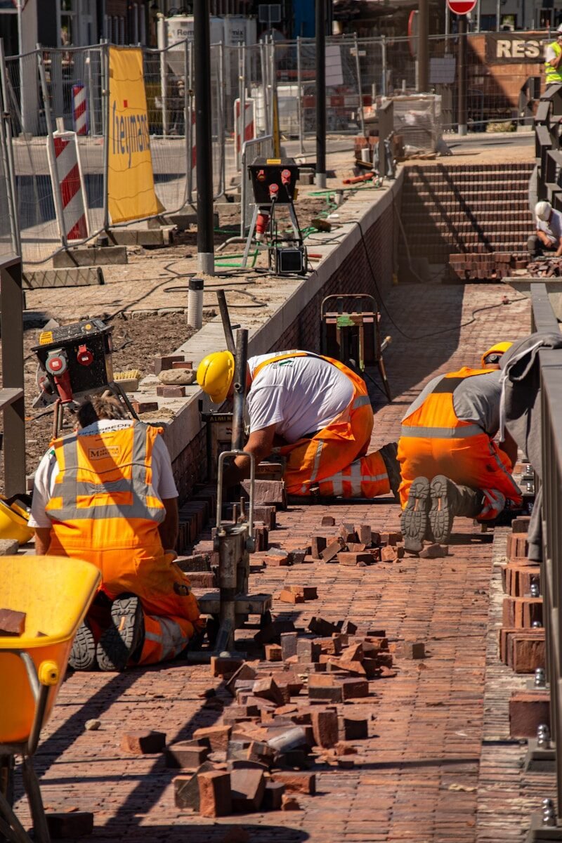 a group of construction workers working on a brick walkway
