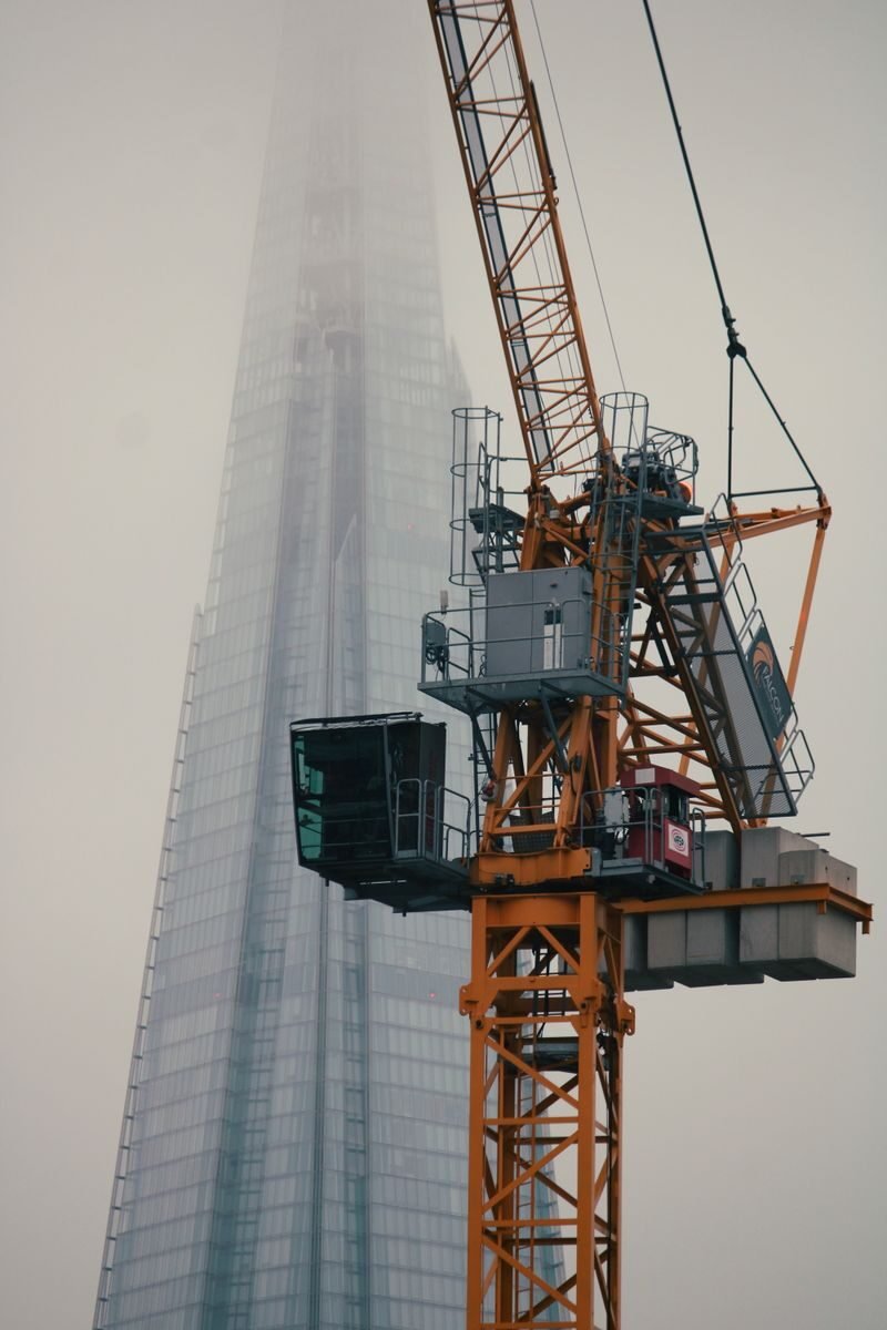 Photo by Sarthak Maji Fog engulfs a construction crane beside The Shard in London's misty skyline.